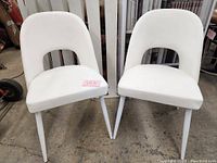 Two white leatherette side chairs front view on concrete floor