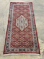 Full view of carpet laid flat on concrete floor showing entire pattern and fringed ends