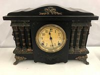 Front view showing the clock face and decorative fluted columns with brass feet on the wooden and marble case.
