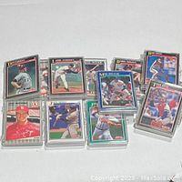 Photo of a group of plastic cases containing vintage baseball cards with visible player images including Don Carman, Larry Andersen, Jim Morris, Max Bielecki, with cards from Topps and Fleer.
