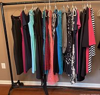 Photo of a rack with 15 assorted women's dresses and one long shirt in various colors and styles, mostly size small.