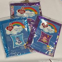 Packaging of Care Bears inflatable chair and 2 pillows with branding and rainbow graphics