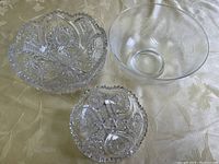 Top view of all three bowls showing clear glass bowl and two intricately patterned crystal bowls with scalloped rims.