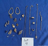 Top-down photo of assorted gold colored jewelry laid out on blue fabric, showing earrings, necklaces, and bracelets.