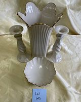 Four Lenox porcelain items on fabric background: one vase, one bowl, and two candle holders arranged upright.