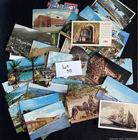 Photo of a collection of older postcards showing different scenic views, wildlife, and landmarks alongside some stamps.