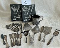 Full lot view showing boxed cake fork sets, tankard mug, assorted serving utensils and forks, spoons.