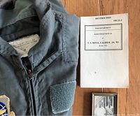 Military coverall partially visible with close up of U.S. Rifle manual booklet on wooden floor