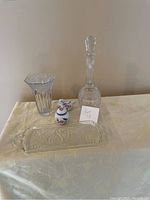 Photo showing clear glass vase, glass decanter with stopper, small porcelain swan plate, small porcelain trinket box with floral and bird design, and rectangular glass tray embossed with swan motifs.
