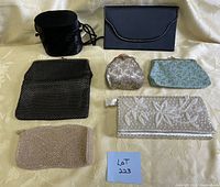 Full view of eight vintage pocketbooks arranged on cream fabric, showing a variety of styles including beaded, embroidered, and fabric designs.
