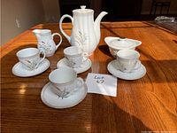 Image showing the entire Yamaha tea set on wooden table in natural light; includes teapot, creamer, sugar bowl with lid, four cups and saucers
