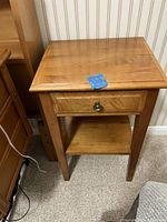 Front view of the wooden end table showing drawer and shelf