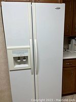 Full exterior front view of white Whirlpool side-by-side refrigerator, showing twin doors and external water/ice dispenser.