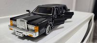 Front angled view of black classic limousine diecast model with open front door and visible grill and headlights.