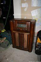 Front view of wooden console radio showing cabinet, grille and dial