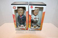 Two sealed bobblehead figures featuring Wayne Gretzky and Brewer in original packaging with clear front window.