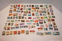 Image of most stamps from the lot spread out showing diversity in countries and designs, some stamps are postmarked.