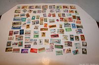 Wide spread view of a large collection of diverse postage stamps arranged on a flat surface, showcasing multiple different designs and countries.