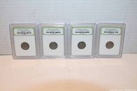 Front view of four slabbed 1943 Lincoln steel cents in protective plastic cases.