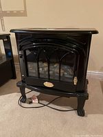 Full view of black Radcliffe electric fireplace stove with decorative legs and glass front door.