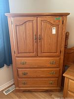 Front view of the tall wood cabinet showing three drawers and two upper doors closed.