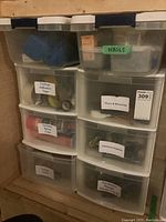 Photo of the stacked plastic storage bins with labeled drawers showing various household maintenance items inside including tapes, pliers, nails, and tapes.