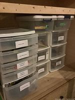 Plastic drawer storage units on wooden shelf, showing multiple drawers with labels.