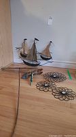 Photo showing three metal sailboat sculptures with jute sails and four metal flowers with gemstone centers placed on the floor
