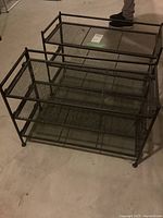 Top view of two matching black metal shoe racks side by side showing mesh shelves and dimensions.