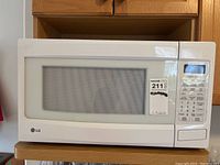 Front view of the LG white microwave showing the operator panel and door with mesh window.