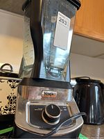 Front view of Ninja blender showing large clear container with measurements and control dial on base.