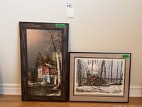 Full view of both framed artworks side by side, showing the water mill painting on the left and the sugar shack print on the right.