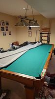 Angled overall view of pool table partially covered with vinyl top cover