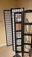 Photo showing the black folding wooden screen with grid pattern behind the frame.