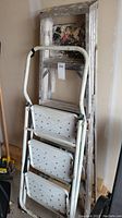 3-step metal stair style step ladder with paint and wear shown leaning upright