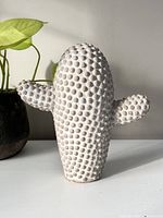 Front view of the white cement cactus statue with textured surface and side arms.