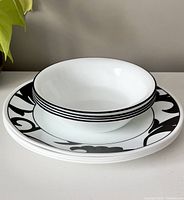 Stacked view of 4 Corelle soup bowls resting on top of 4 Corelle plates showing size difference and design