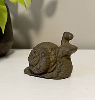 Side angle view showing detailed raised snail head, neck and body design with flat angled base for doorstop use.
