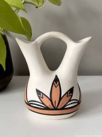 Front view of white Pueblo wedding vase with terracotta and black feather design