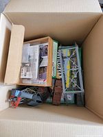 Top view of the cardboard box showing various train accessory items, boxed kits, and bridge parts inside