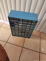 Front view of blue storage cabinet with multiple small drawers