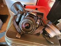 Front angled view of Canon EOS Elan 7N camera with attached Sigma 28-200mm lens, showing the camera body, lens, and Canon branding.