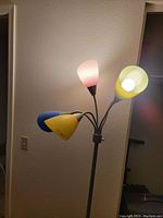 Floor lamp showing all five light heads with multi-color cone-shaped shades including pink, yellow, blue, and green attached to a central metal pole.