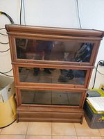 Front view of wooden lawyer's bookcase with three stacked glass doors and a paneled base.