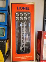 Front view of boxed Lionel Floodlight Tower model 16402 with eight round lights visible through plastic window.
