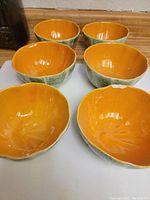 Set of 6 ceramic bowls designed as cantaloupes showing bright orange interior and textured green exterior.