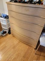 Photo showing a full front view of the mid century wooden dresser with curved drawer fronts and smooth light wood finish on a hardwood floor.