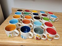 Photo showing 20 colorful Starbucks mugs from the Been There Series arranged on a countertop, each with a unique location themed design.
