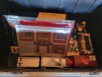 Photo showing toy freight car building design and various toy vehicles in a tote