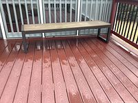Full front view of the outdoor bench showing the faux wood seat and metal frame on a porch deck.